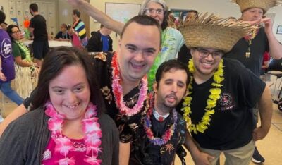 A group of neurodivergent adults having a party with plastic lei on.