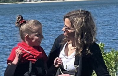 A teacher sitting with her student smiling at one another.