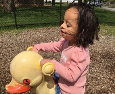 A young student riding on a playground duck